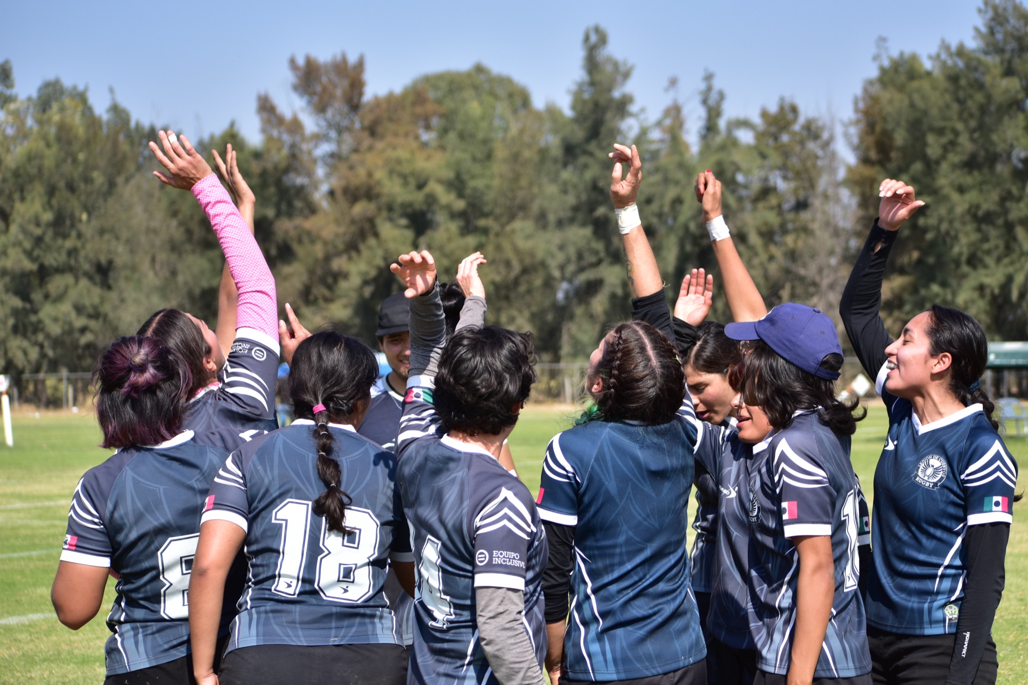 Jugadoras levantan las manos en una reunión de equipo